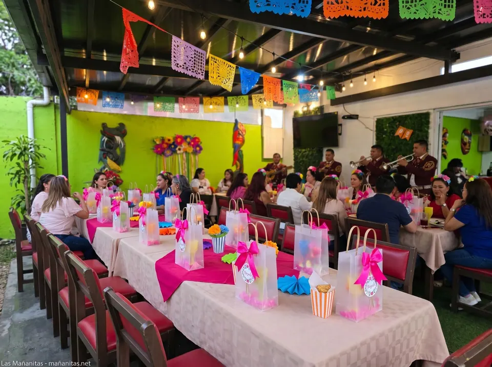 Mesa larga decorada con papel picado, flores y bolsitas de regalo para una celebración
